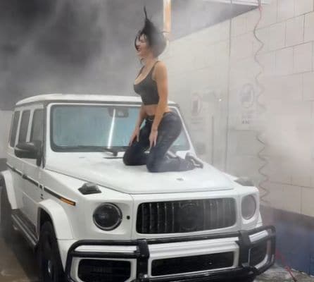 vrouw op motorkap Mercedes G-klasse lekker wassen
