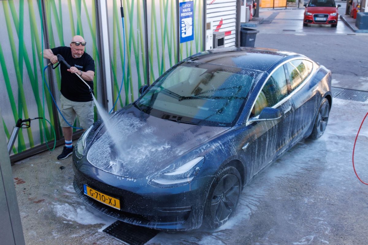 Luc spuit Tesla Model 3 af in wasbox, autowassen, schoon
