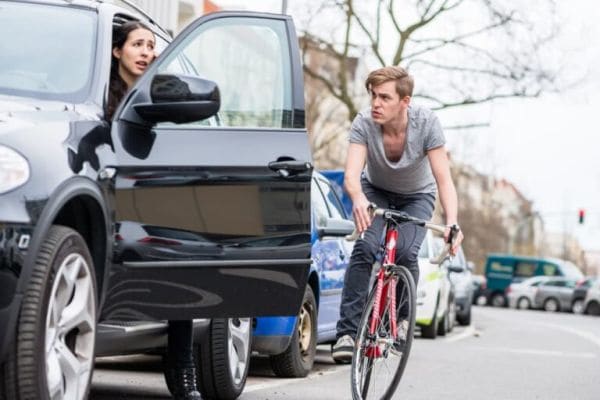 Openen portier auto terwijl fiets eraan komt